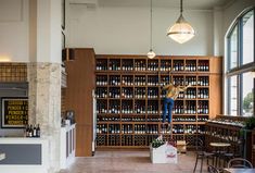 a woman standing in the middle of a room with lots of wine bottles on shelves