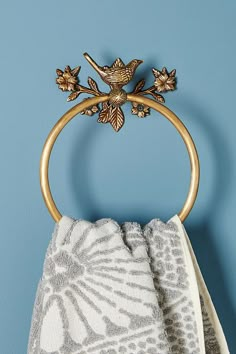 a towel ring with two birds on it hanging from a blue wall next to a white and gray towel