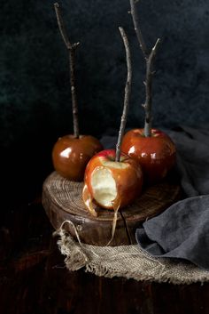 three apples are sitting on a wooden plate