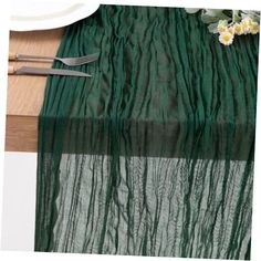 the table is set with silverware and green sheer curtains, along with white flowers