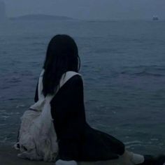 a woman sitting on top of a rock next to the ocean