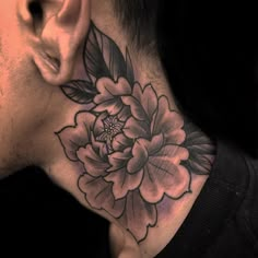 a man's neck with a flower tattoo on the back of his neck and ear