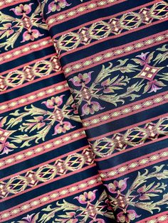 a close up view of a tie with designs on the side and in pink, blue and gold colors