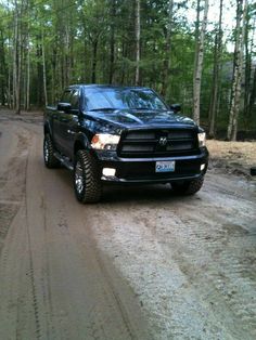 a black ram truck driving down a dirt road