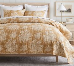 a bed with yellow and white comforters in a bedroom