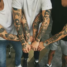 several men with tattoos on their arms and hands are standing in a circle holding each other's hands