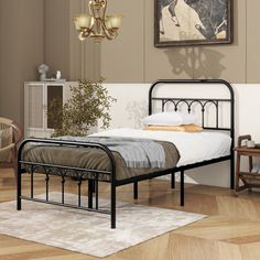 a black metal bed frame in a room with hardwood floors and walls, along with a painting on the wall