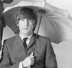 a man in a suit and tie holding an umbrella over his head while standing next to another man