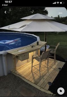 an above ground swimming pool with umbrellas and chairs on the deck next to it