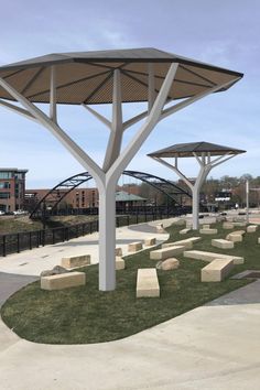 an empty park with benches and umbrellas on the grass