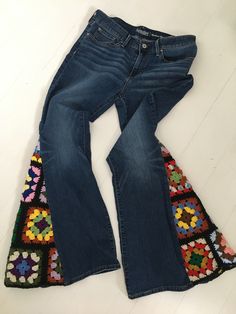 the jeans are lined up on the floor with different colored crochet patterns around them