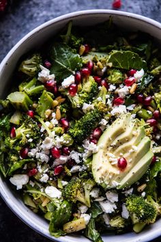 a white bowl filled with broccoli, cheese and pomegranates