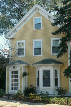 a large yellow house with white trim and two story windows on the second floor is shown