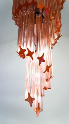 a pink chandelier with stars hanging from it's sides and the lights turned on