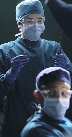 two doctors in scrubs and masks are performing surgery