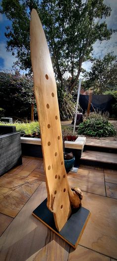 a large wooden surfboard sitting on top of a black mat next to a tree