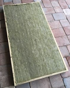 a piece of wood sitting on top of a brick floor next to a white dog