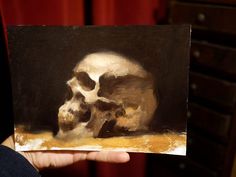 a person holding up a painting with a skull on it