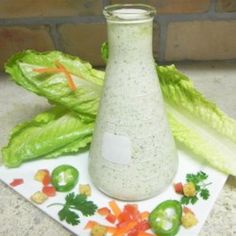 some lettuce and carrots on a plate next to a vase with dressing