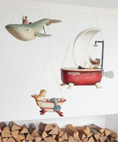 some ornaments are hanging from chains in the shape of boats and people on wooden logs