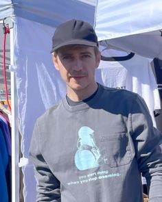 a man wearing a baseball cap standing in front of a tent