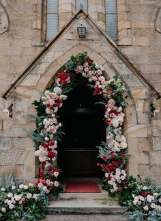 a church door decorated with flowers and greenery