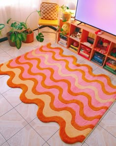 an orange and pink rug is on the floor in front of a flat screen tv