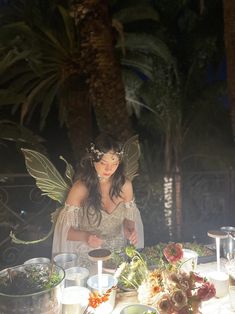 a woman dressed as a fairy preparing food at a table with plates and bowls on it