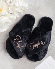 a pair of black slippers sitting on top of a table next to a white flower