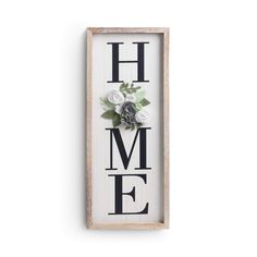 a wooden sign that says home with flowers on the front and back of it, hanging on a wall