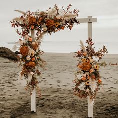 an outdoor ceremony setup on the beach with flowers and pamolite in front of it