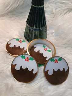 four decorated cookies sitting on top of a white furnishing next to a vase