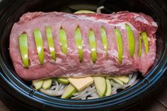 a large piece of meat sitting on top of some onions and cucumber slices