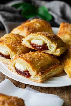 several pastries on a white plate sitting on top of a wooden table with napkins