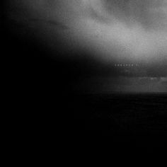 a black and white photo of an airplane flying in the sky with dark clouds above it