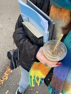 a woman holding a cup with a straw in her hand while walking down the street