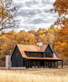 a house in the middle of a field surrounded by trees with fall foliage on it