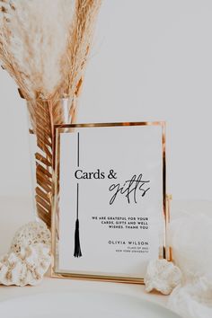 a card and gift box sitting on top of a white plate next to some feathers