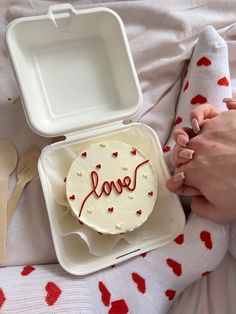 someone is holding their hand over a cake with the word love on it in a plastic container