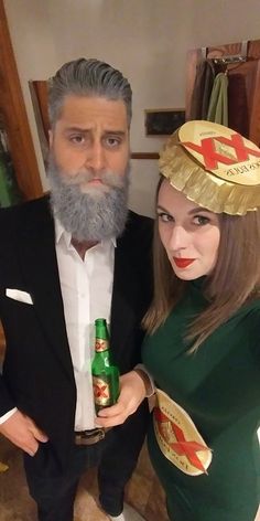 a man and woman dressed up in costumes holding beer bottles, posing for the camera