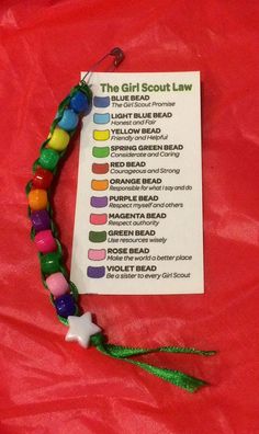 the girl scout's bracelet is made out of beads and plastic beads on a red sheet