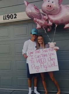 a man and woman standing next to each other holding pink balloons with pigs on them