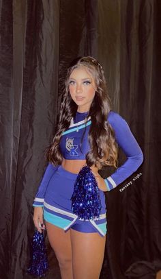 a beautiful young woman in a blue cheerleader outfit standing next to a black curtain