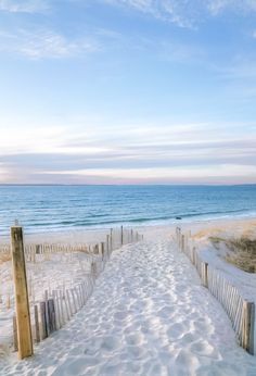 a sandy path leading to the ocean on a sunny day