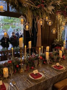 a long table is set with candles, plates and place settings for christmas dinner guests