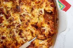 a casserole dish with cheese and meat in it on a red napkin next to a fork