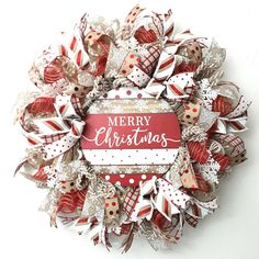 a red and white christmas wreath with merry lettering on the front, surrounded by bows