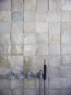 three silver and black wall mounted shower faucets in front of a tiled wall