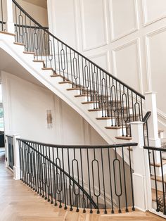 an elegant staircase with wrought iron railing and wood flooring