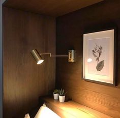 a lamp is on above a bed in a room with wood paneling and white sheets